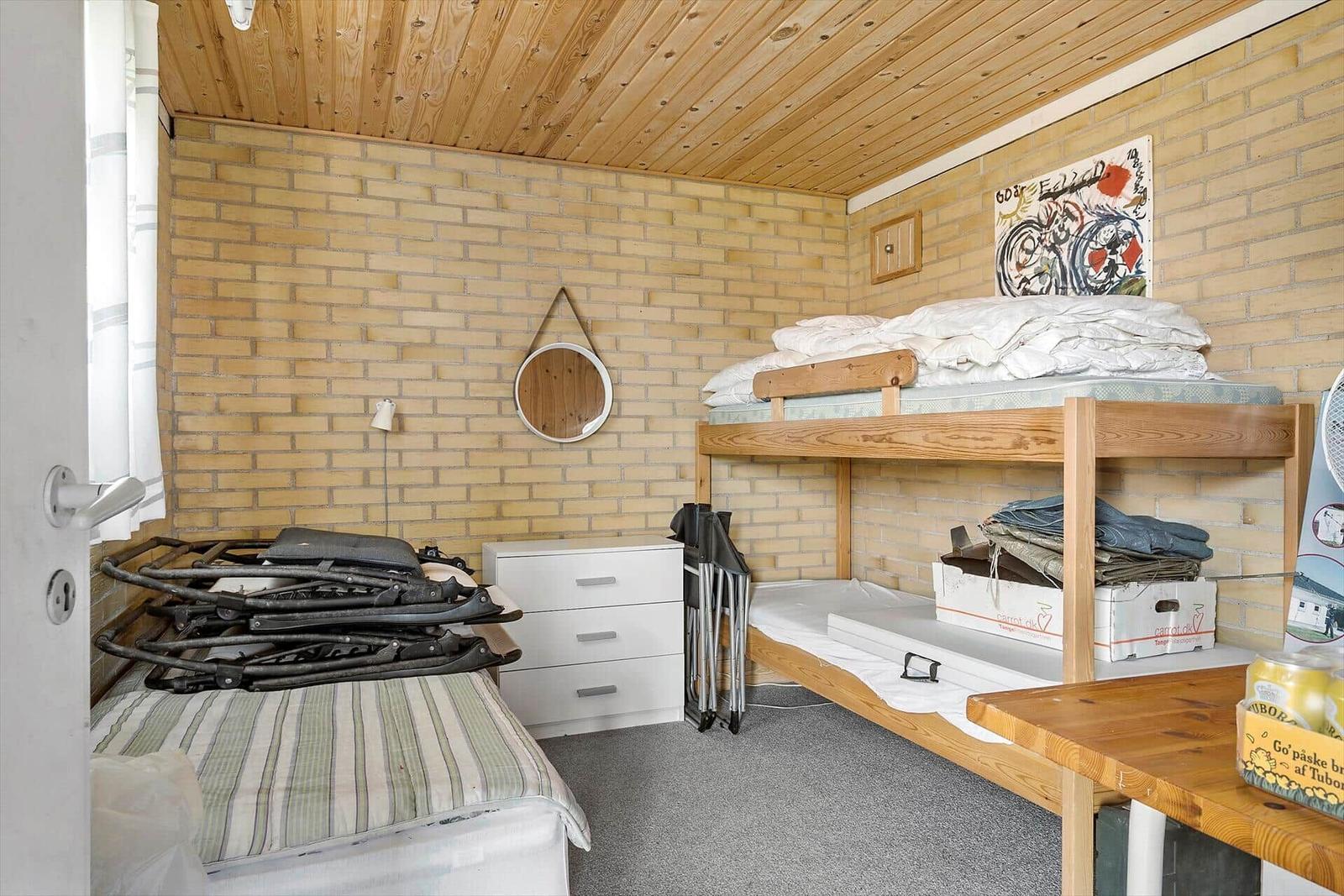 Zimmer mit Doppelstockbett, Kleiderschrank und Holzdecke.
