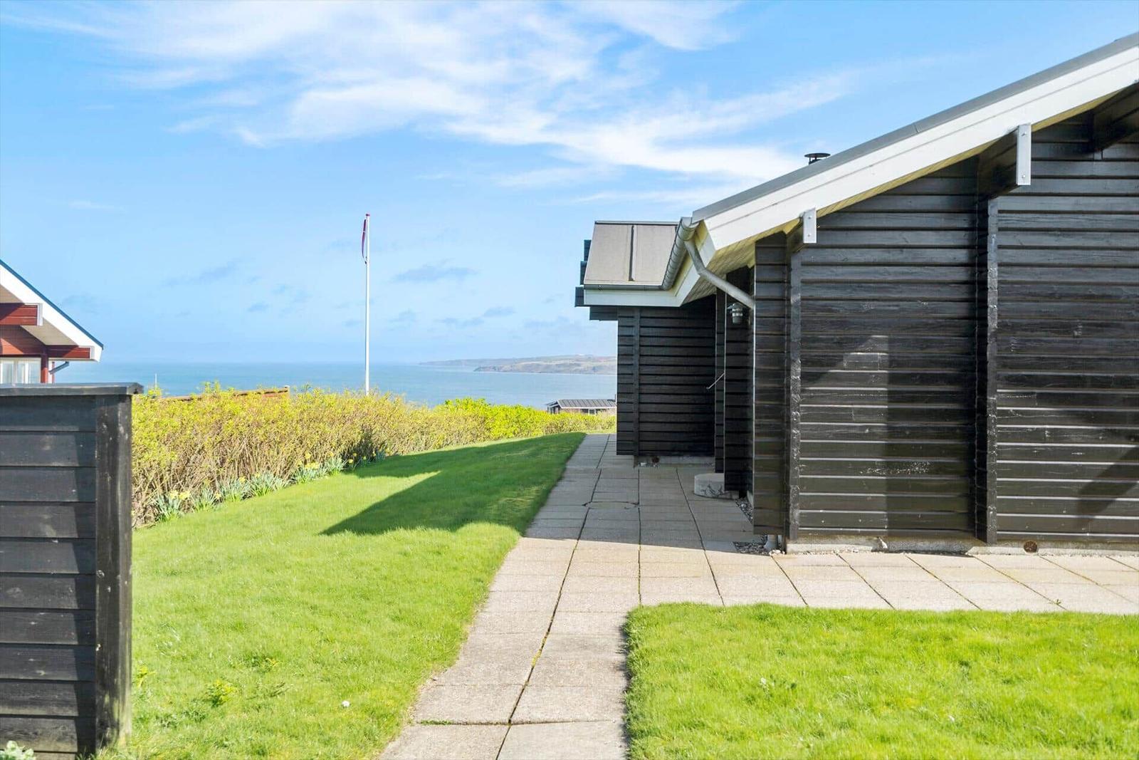 Haus mit Blick auf das Meer und grünen Gartenweg.