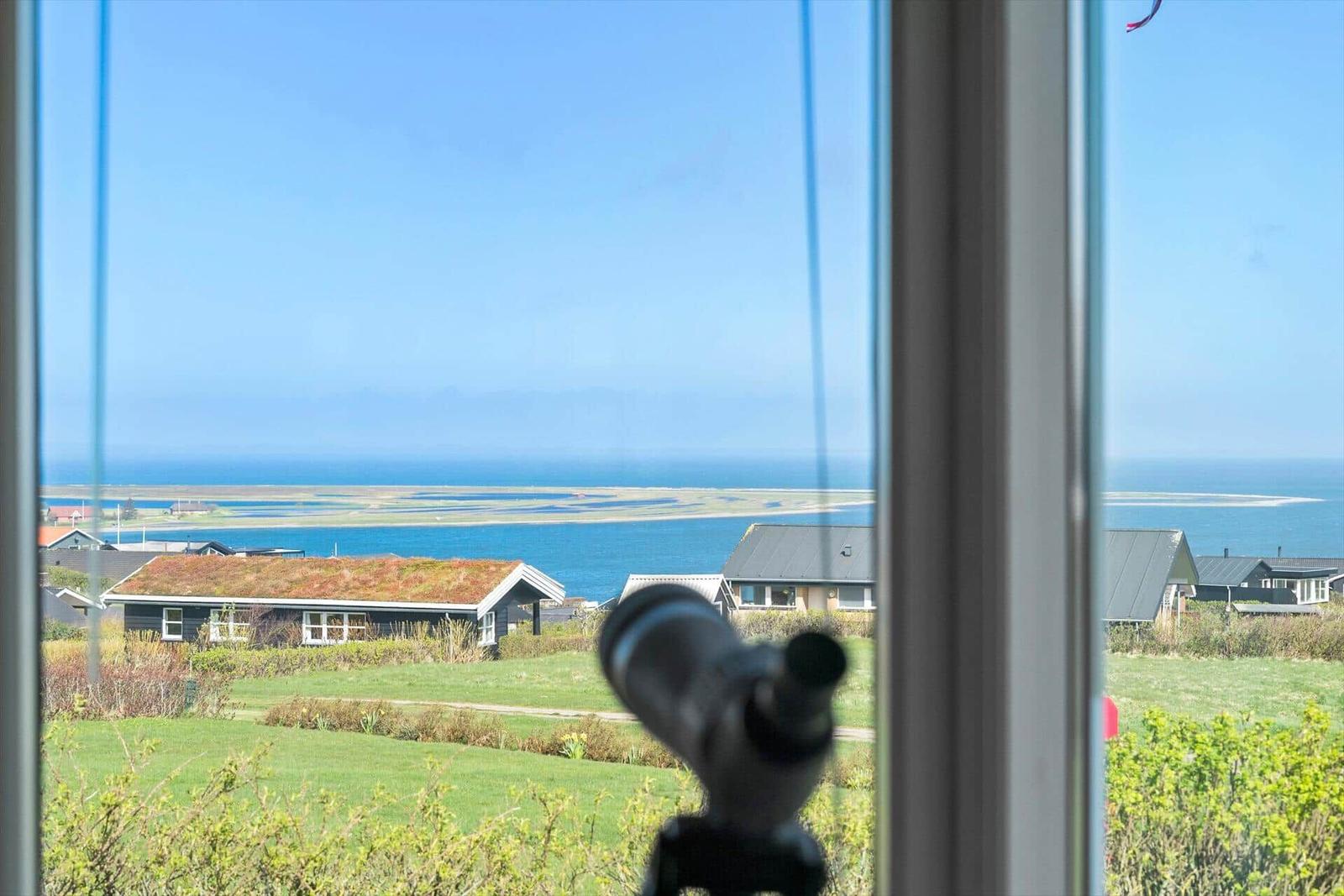 Durch das Fenster ist ein Blick auf das Meer und eine Insel mit Häusern zu sehen.