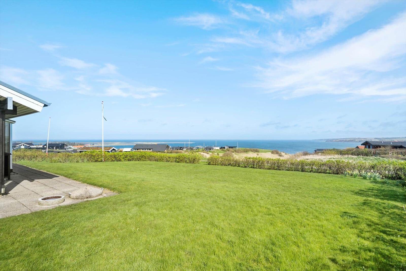 Grüner Garten mit Blick auf das Meer und Ferienhäuser.