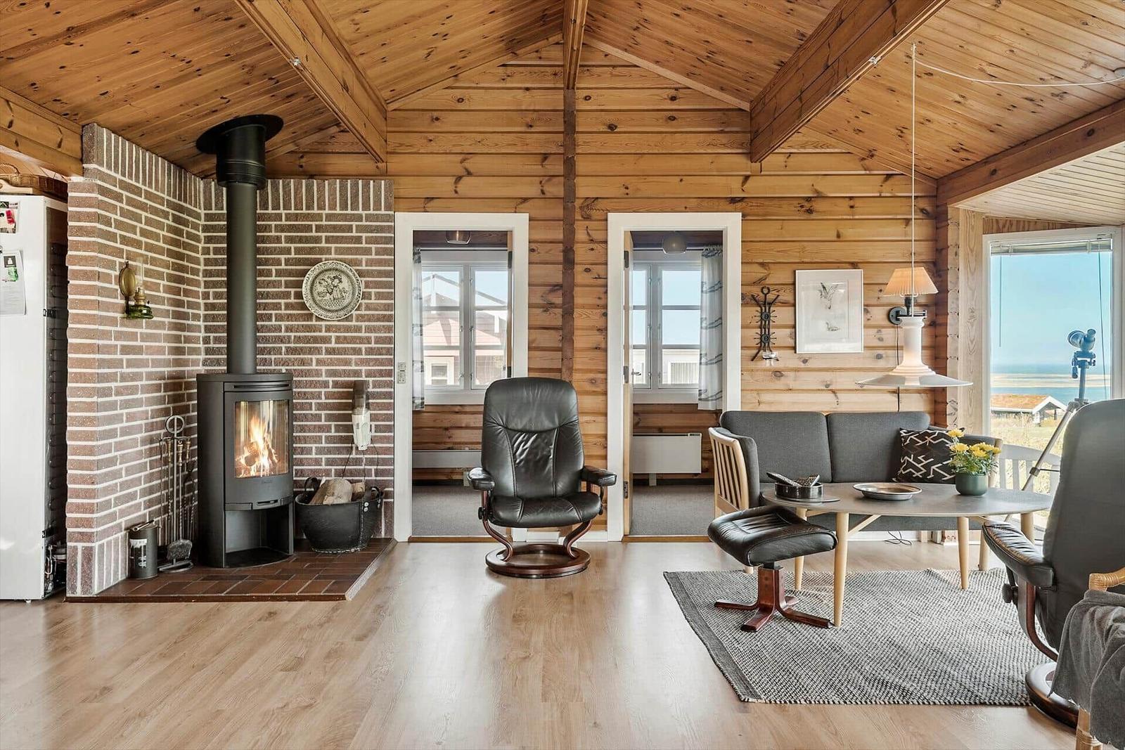 Wohnzimmer mit Holzdecke, Kamin und Sitzgelegenheiten.