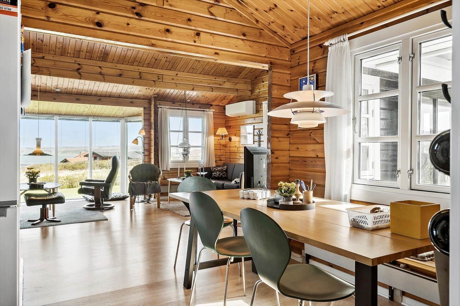 Essbereich mit Holztisch und Stühlen. Holzwände und -decke. Fenster mit Blick auf Landschaft.