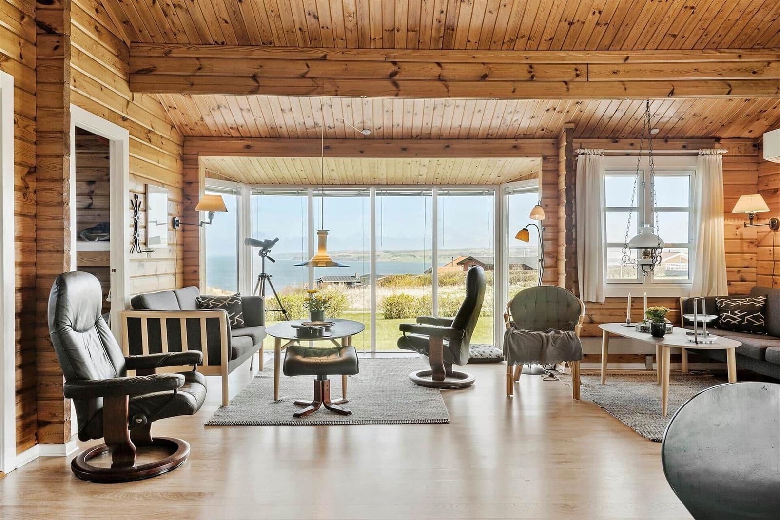 Wohnzimmer mit Holzwand, großem Fenster und Meerblick.