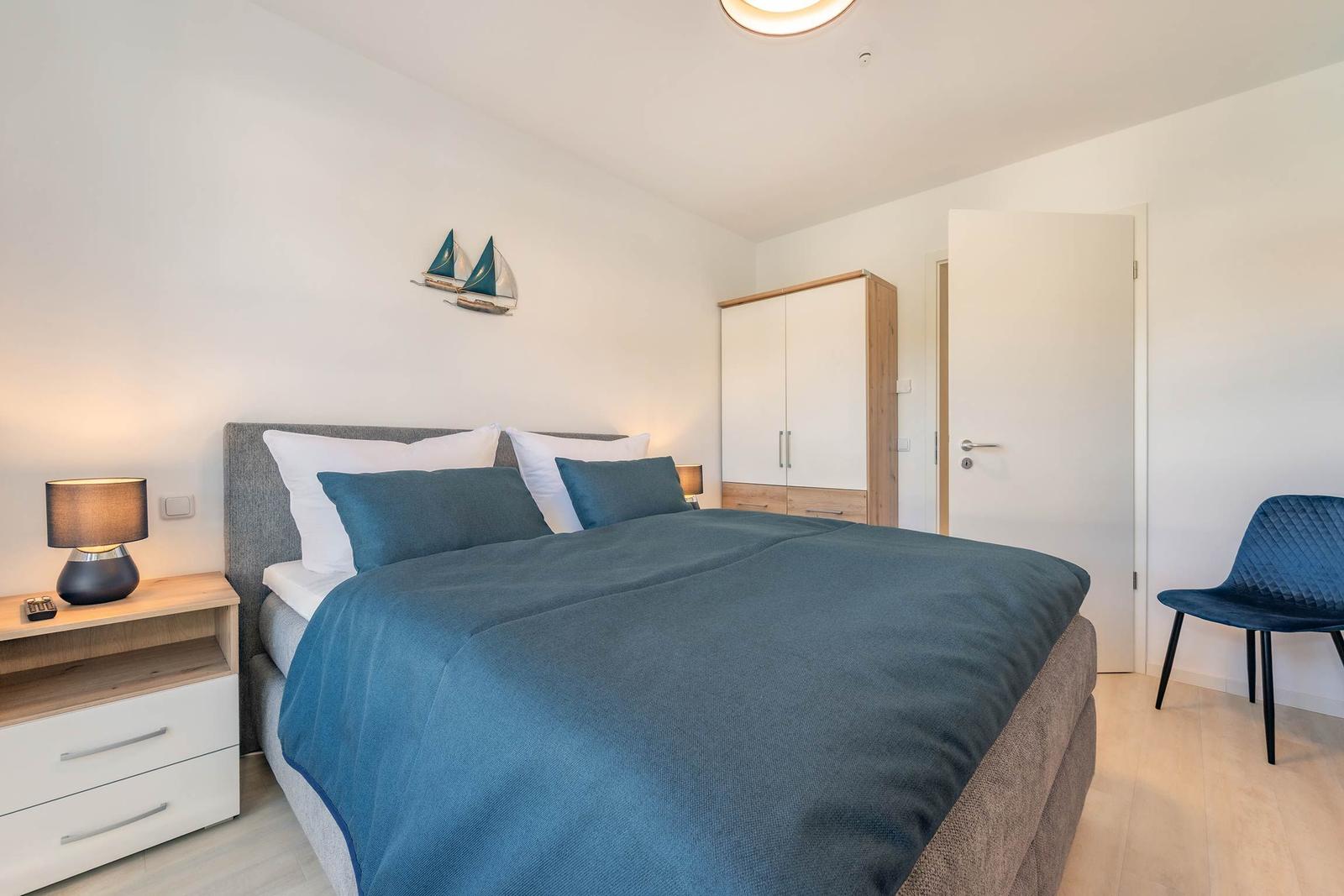 Schlafzimmer mit Bett, Nachttisch, Kleiderschrank und Stuhl.