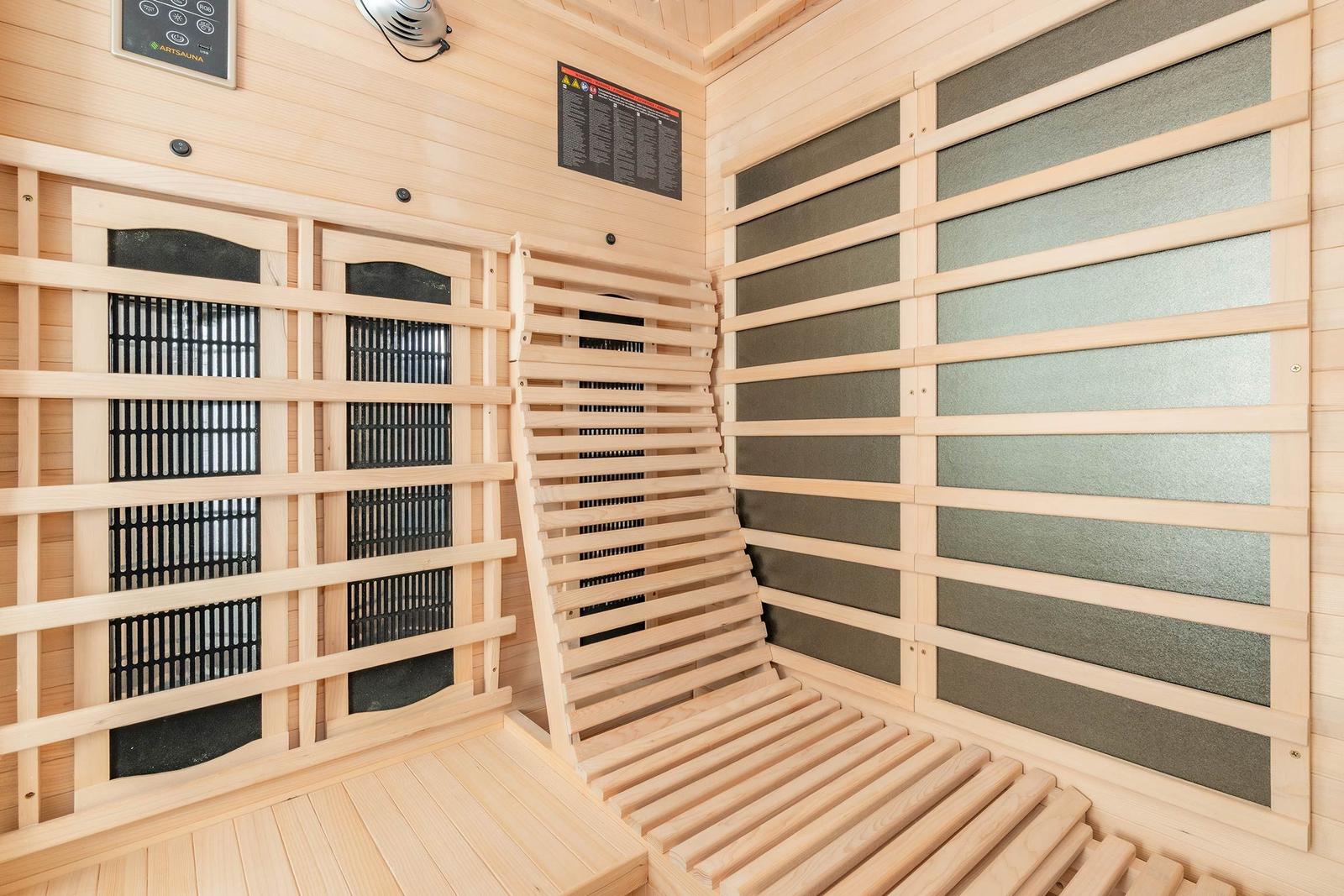 Innere eines Holzsaunas mit Sitzbänken und Heizung.