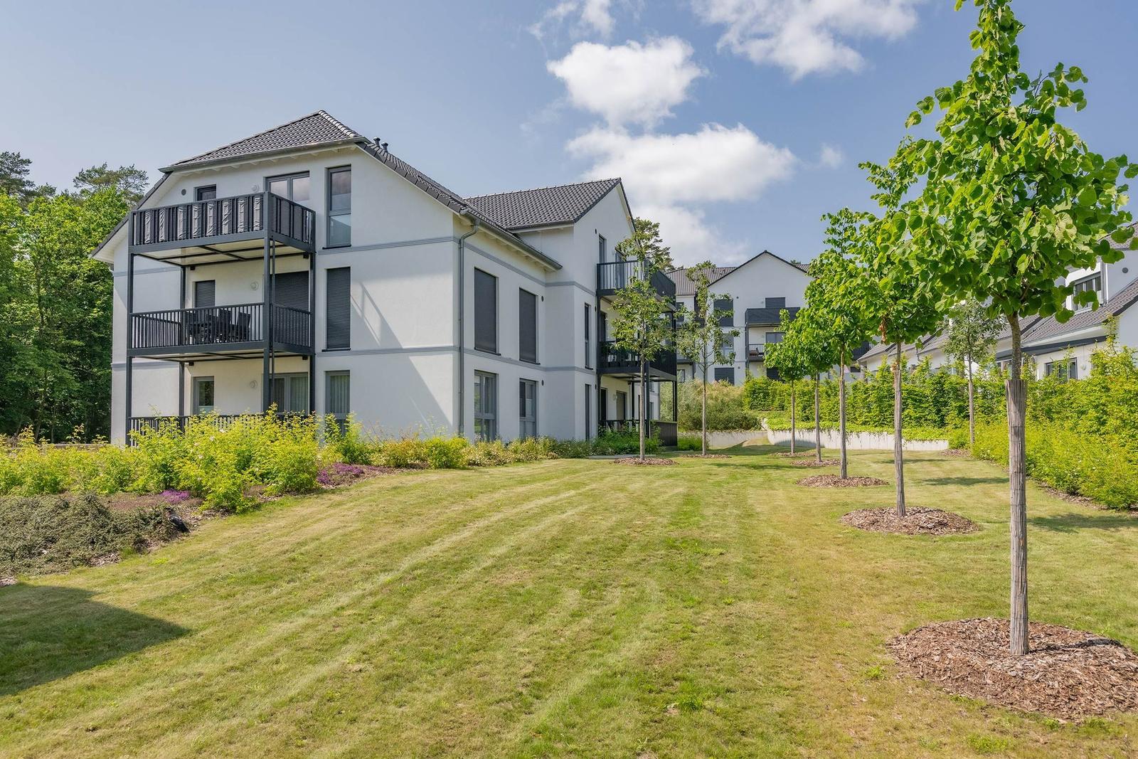 Moderne Wohnanlage mit Balkonen und grünem Gartenbereich.