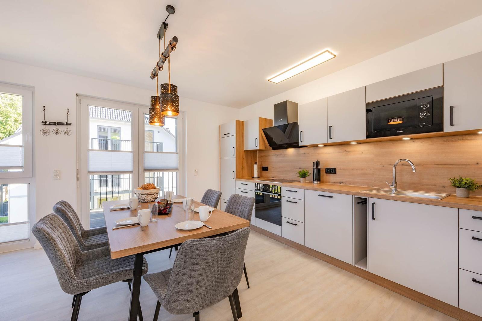 Küche mit Esstisch, weißen Schränken und Holzoberflächen.