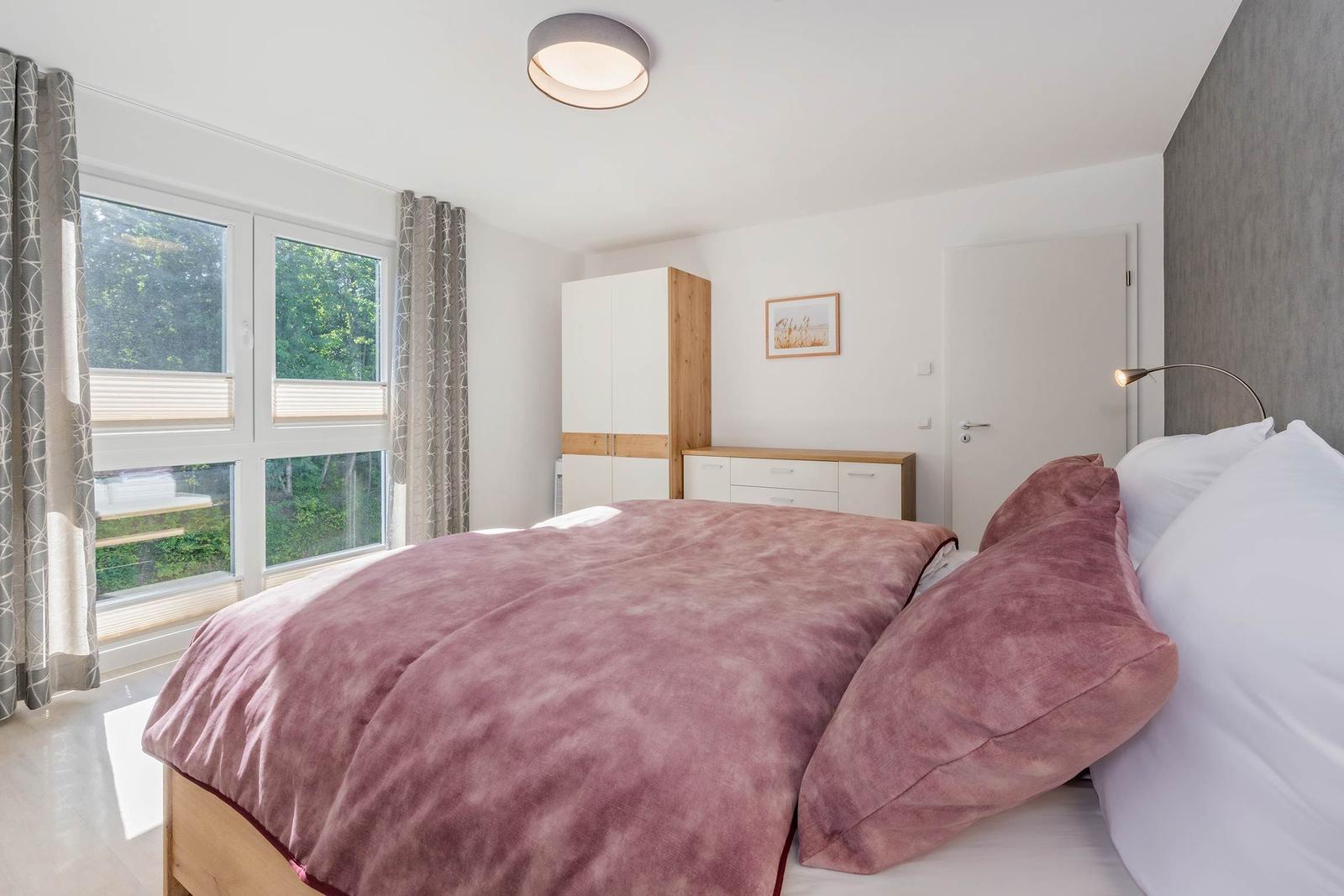 Schlafzimmer mit Bett, Fenster und Schrank.