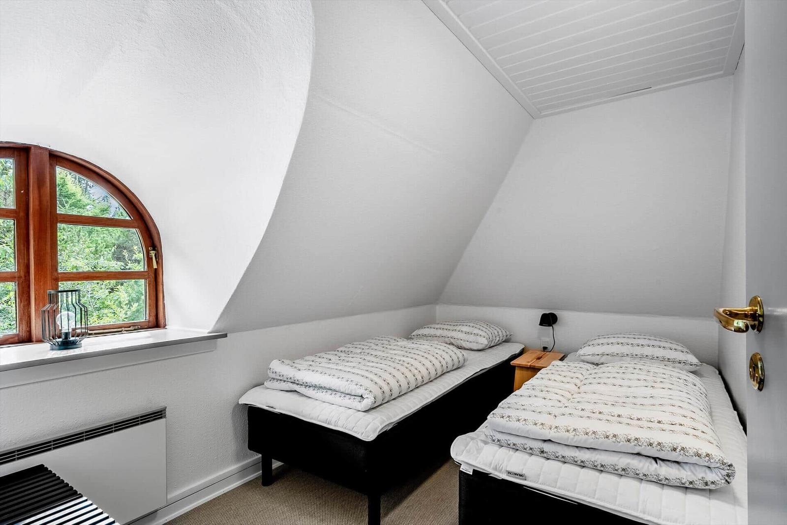 Zimmer mit zwei Betten, Holzfenster und Heizung.