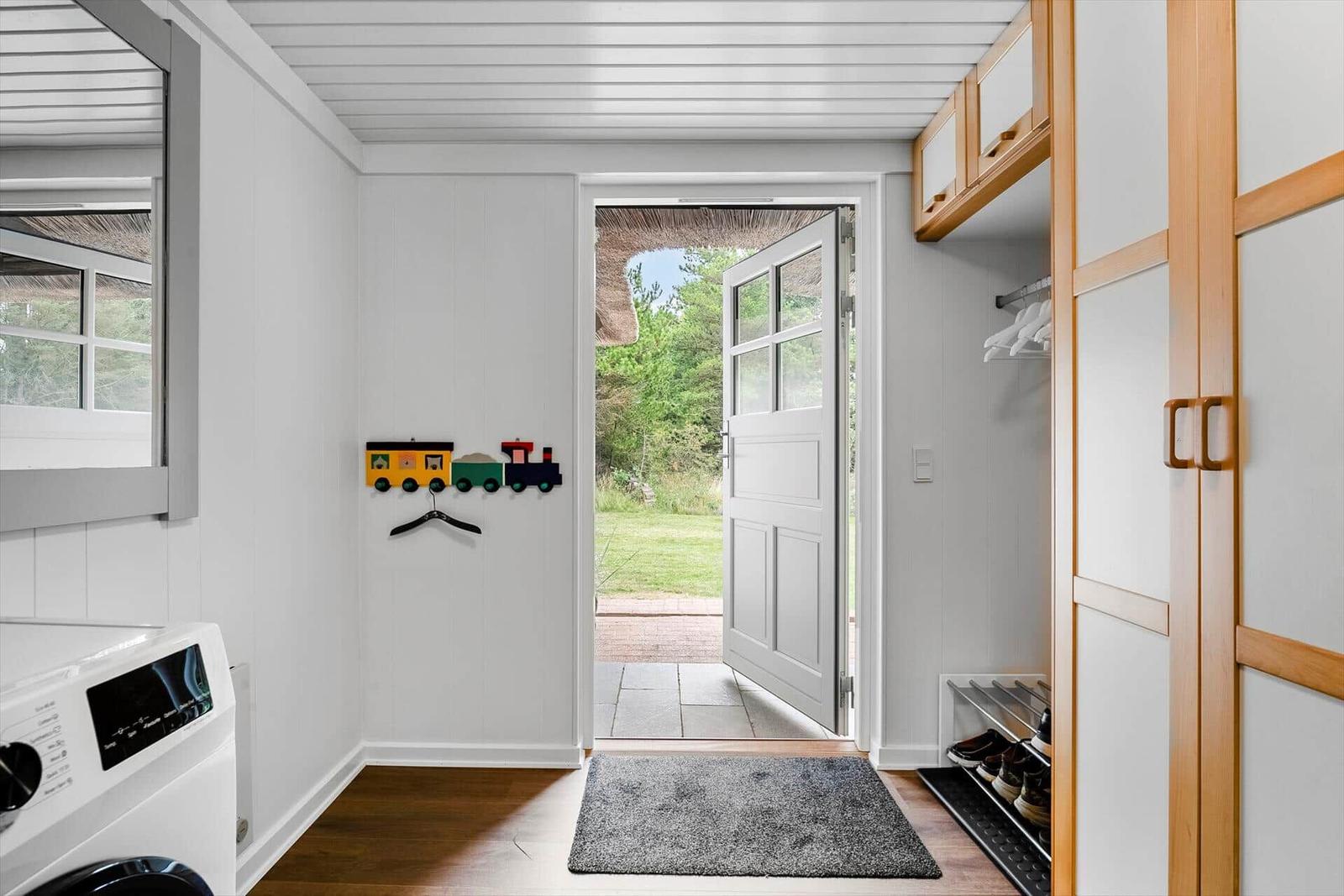 Eingangsbereich mit Waschmaschine, Schuhschrank und Blick auf den Garten.