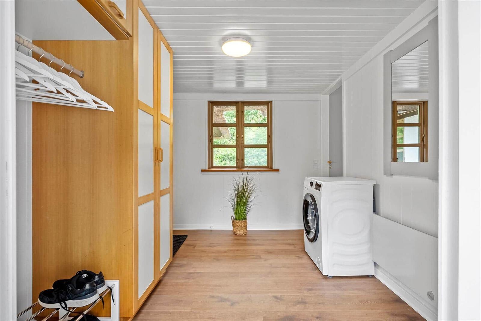 Wohnraum mit Kleiderschrank, Waschmaschine und Fenster.