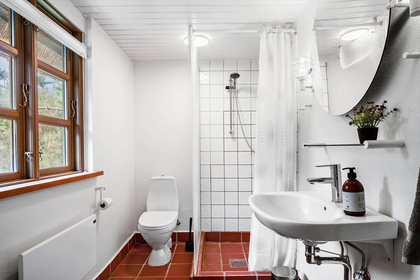 Badezimmer mit Toilette, Dusche und Waschbecken. Fenster, Spiegel und Badewanne.