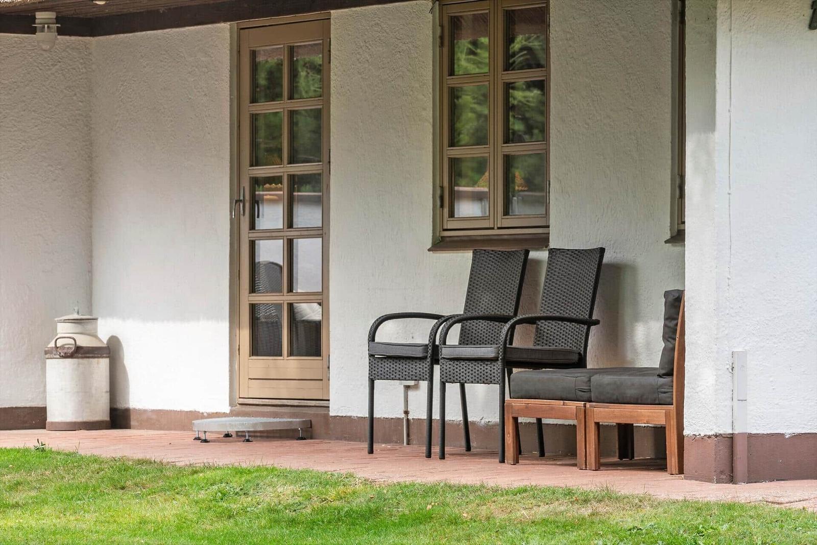 Terrasse mit Stühlen, Tür und Fenster an weißer Wand
