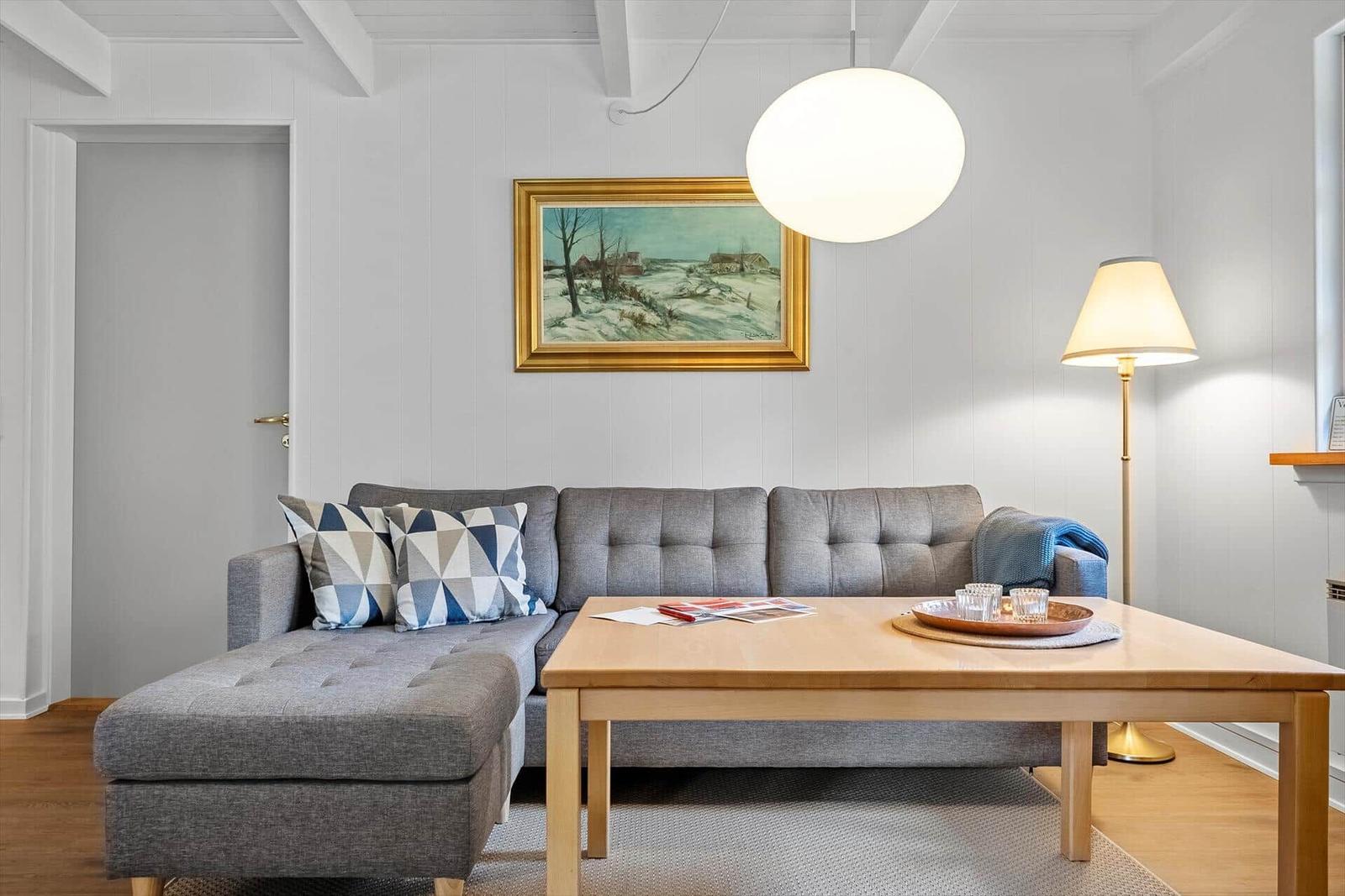 Ein Wohnzimmer mit grauem Sofa, Holztisch und Wandbild.