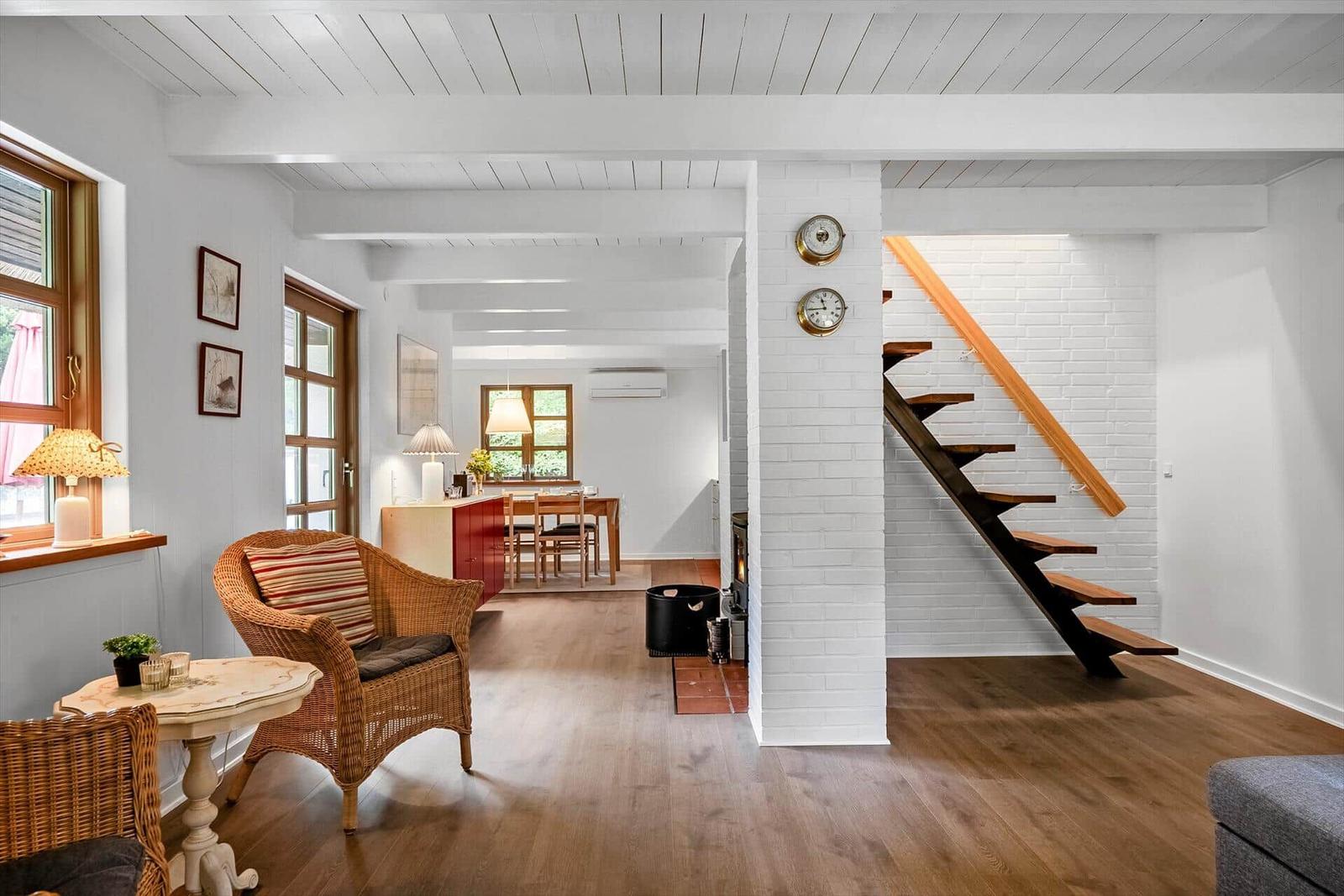Wohnbereich mit Holzboden, Sitzgelegenheiten und Treppe zur oberen Etage.