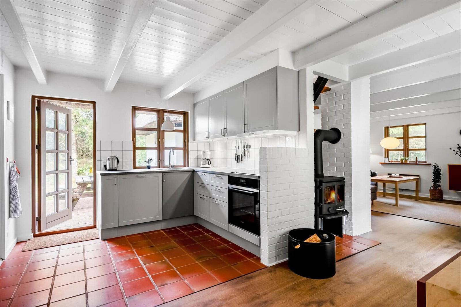 Küche mit Holzfußboden und Backofen. Durchgang zu Wohnzimmer mit Tisch.