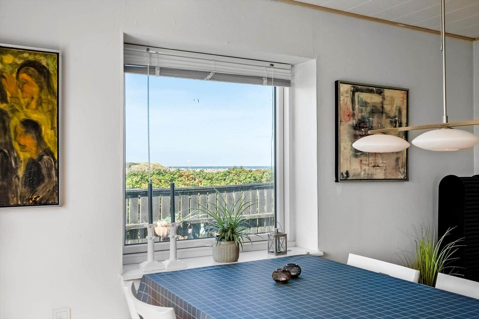 Esszimmer mit Blick auf den Strand und Meer. Tisch mit blauer Tischdecke und Wandbildern.