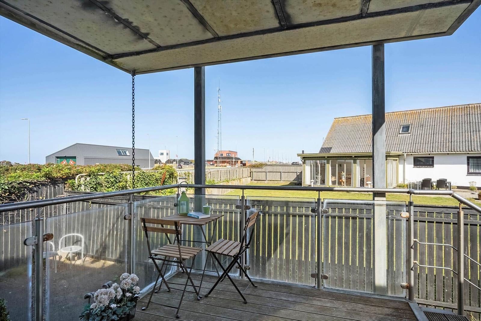 Terrasse mit Tisch und Stühlen, Blick auf Garten und Nachbarhäuser.