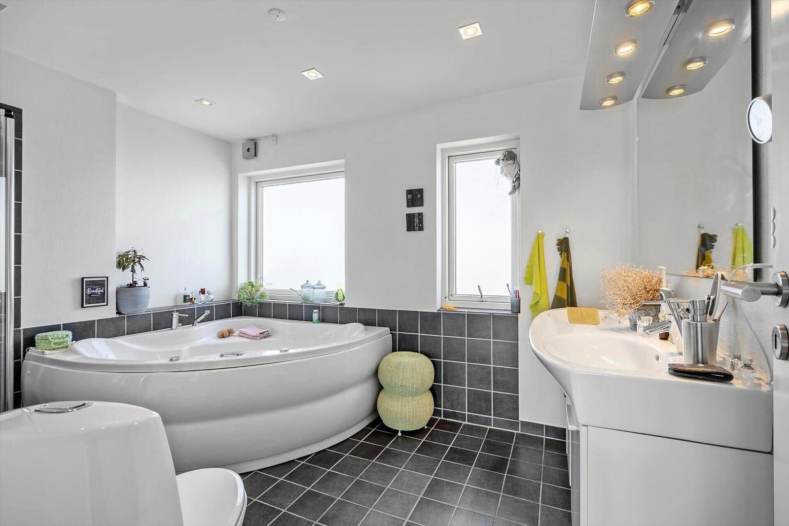 Bad mit Whirlpool, Waschbecken und Fenstern.