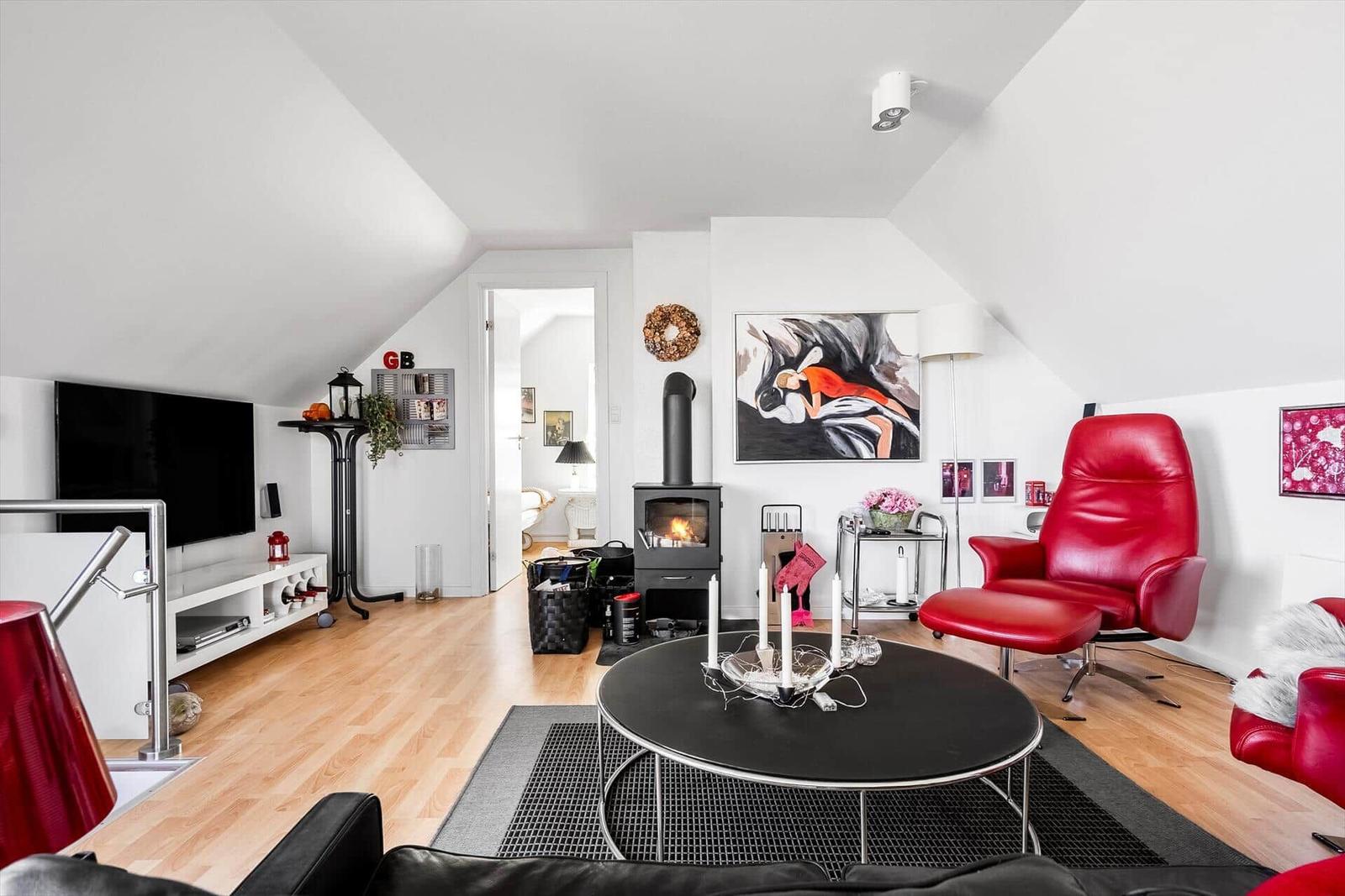 Wohnzimmer mit Kamin, rotem Sessel und Fernseher an der Wand.