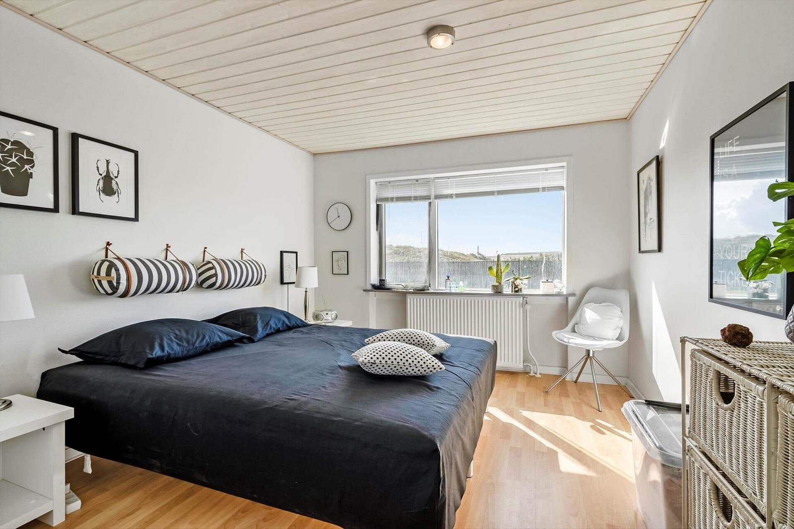 Schlafzimmer mit Bett, Fenster und weißen Wänden.