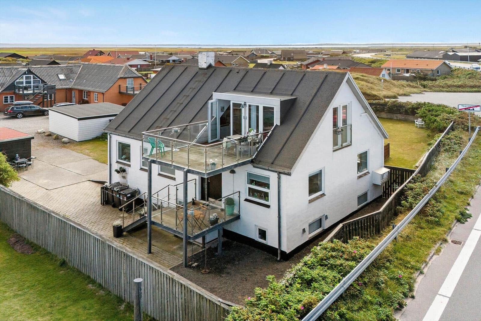 Modernes weißes Haus mit Balkon und Terrasse in ländlicher Umgebung.