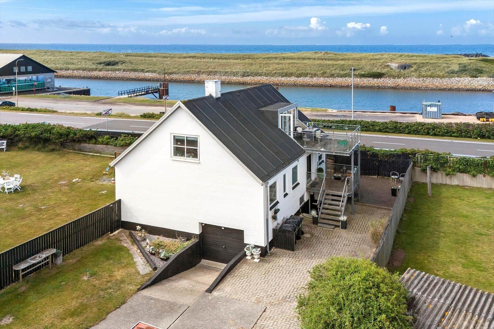Wohnhaus mit Terrasse und Blick auf Wasser und Strand.
