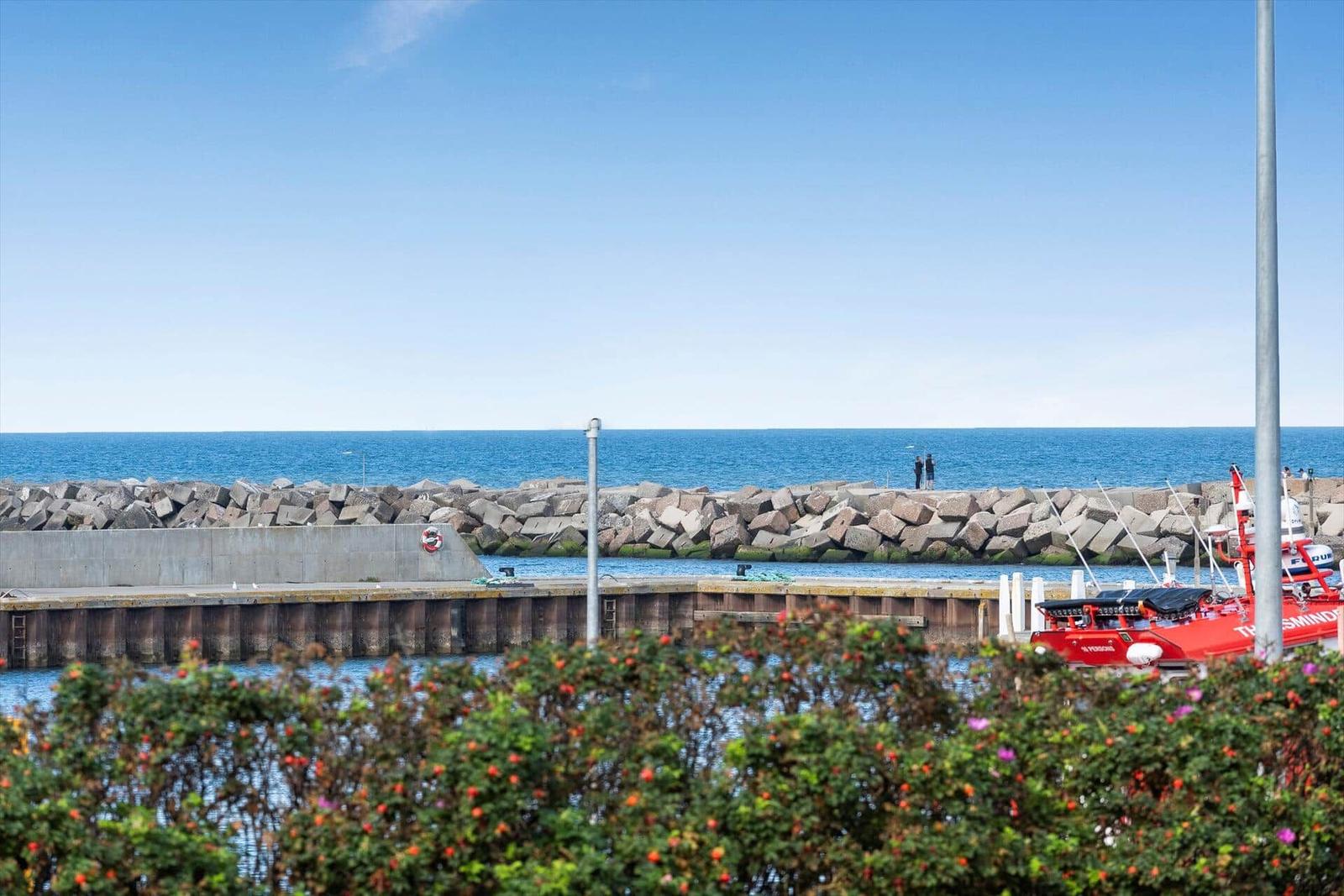 Rotes Boot liegt am Hafen, Blick auf das Meer und Steinschutzwall.