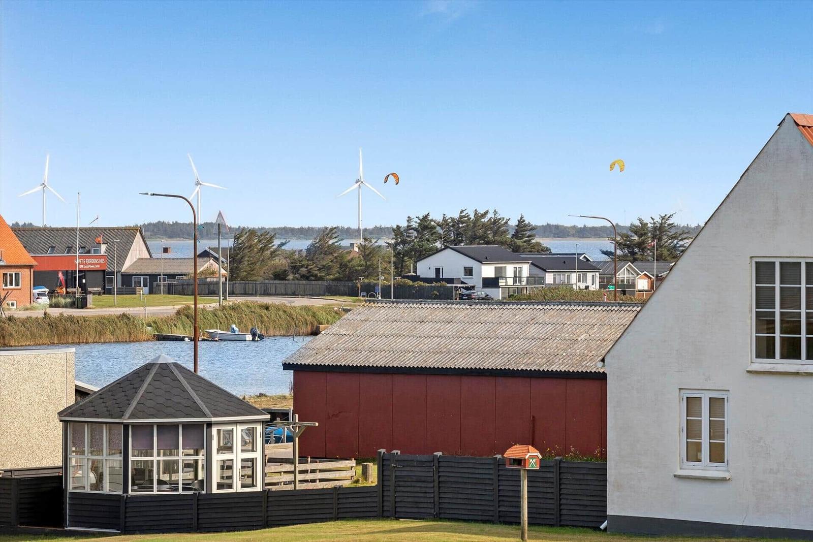Haus mit Blick auf Wasser, Windräder und Kitesurfer.