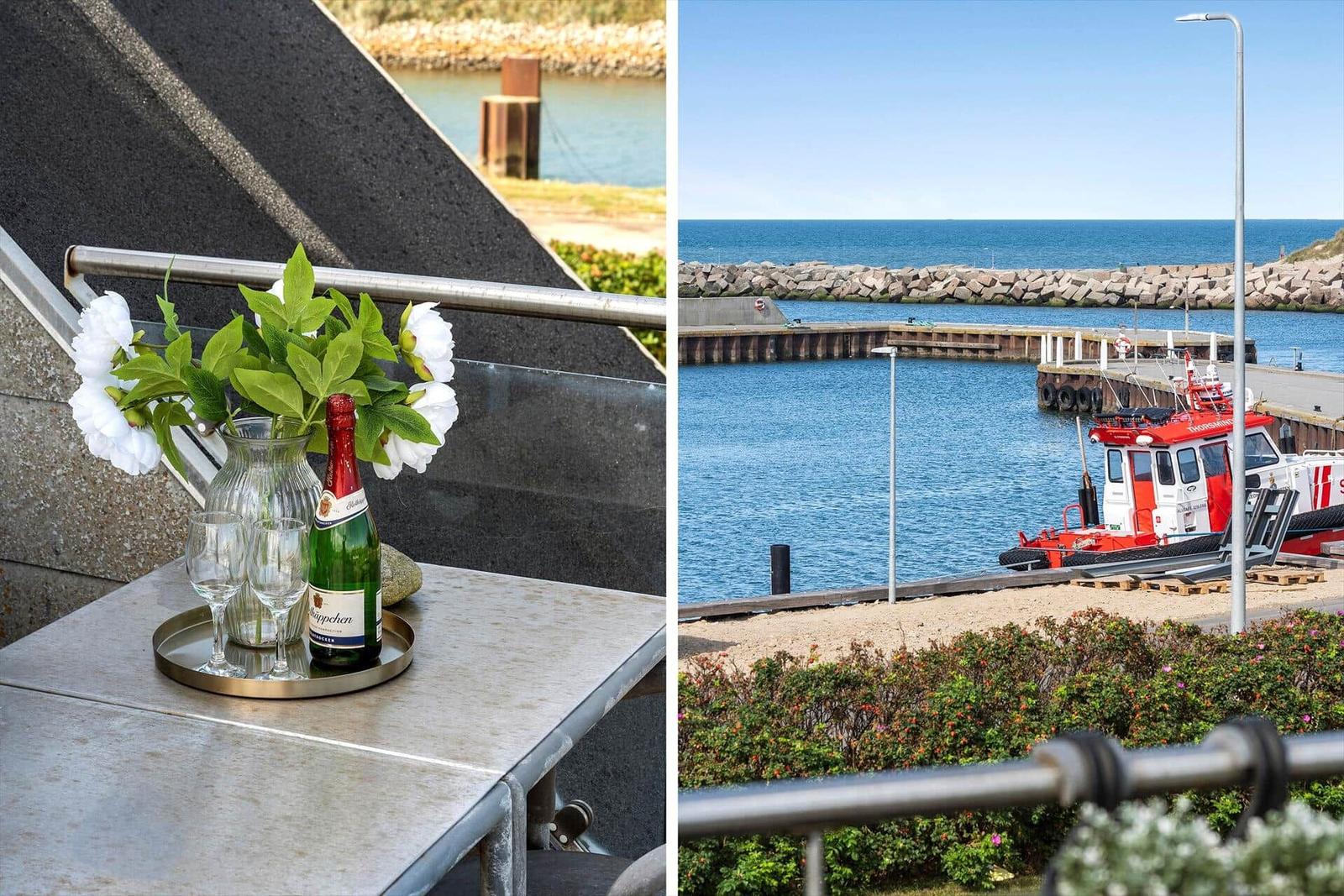 Terrasse mit Blumen und Sekt, Blick auf Hafen mit Rettungsboot.