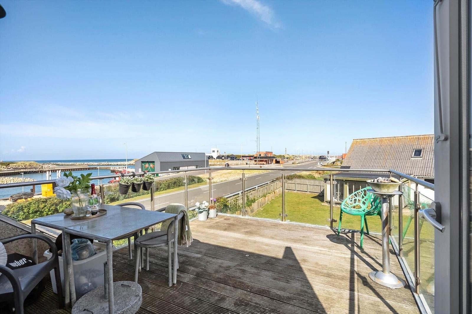 Terrasse mit Tisch, Stühlen und Blick auf Hafen und Straße.