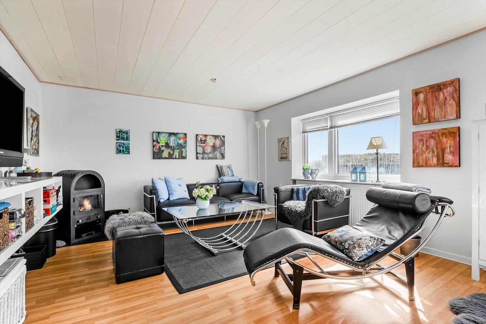 Wohnzimmer mit Sofa, Liegesofa und Kamin. Fenster mit Blick auf Wasser.