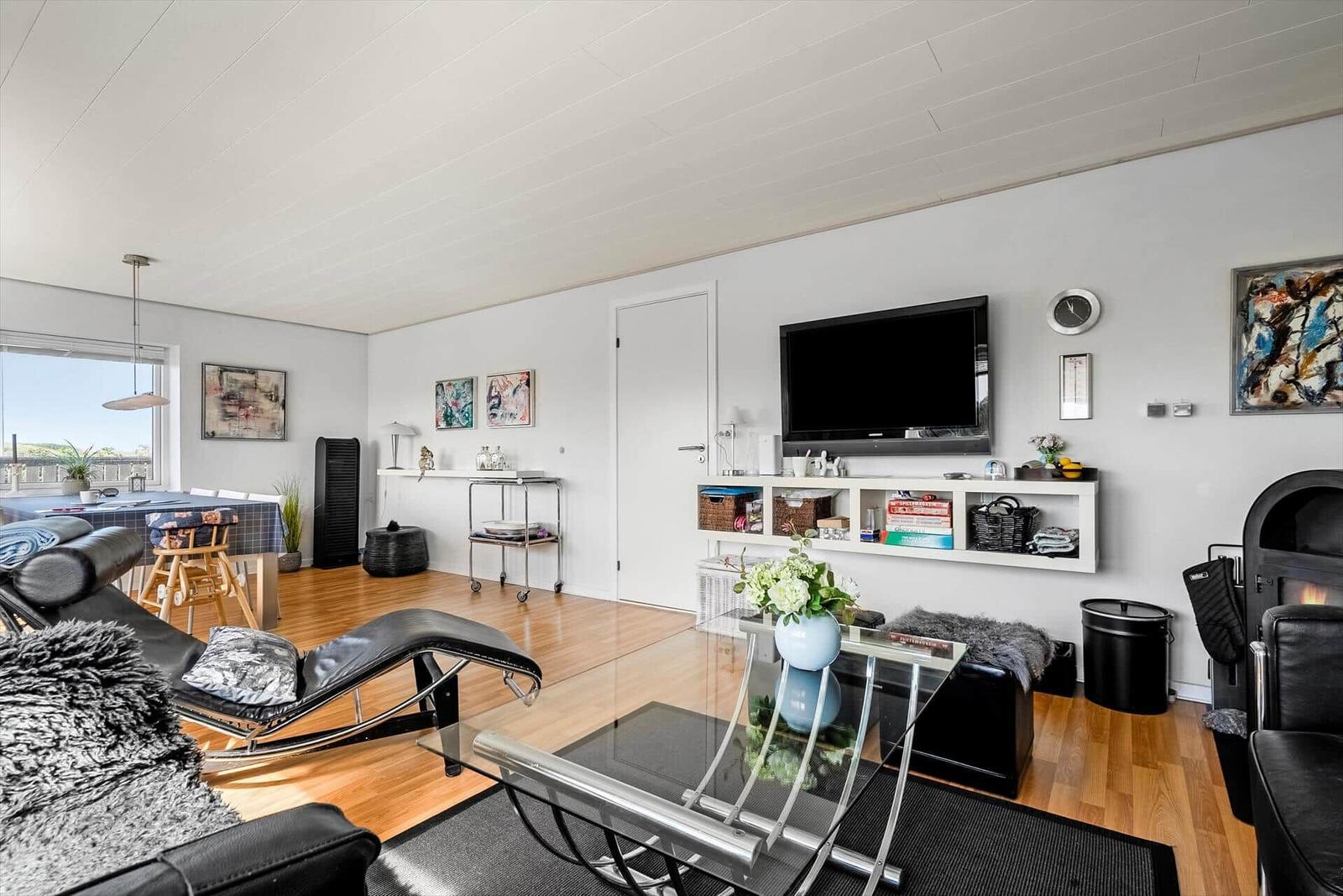 Wohnzimmer mit Fernseher, Glas-Tisch und Sitzgelegenheiten.