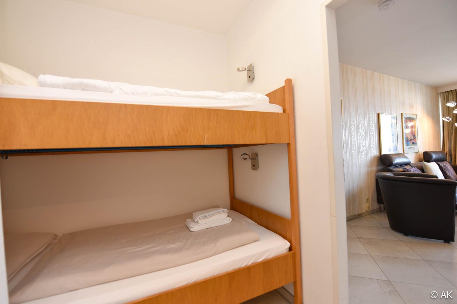 Ein Schlafzimmer mit Doppelstockbett und angrenzendem Wohnbereich mit Ledersofa.