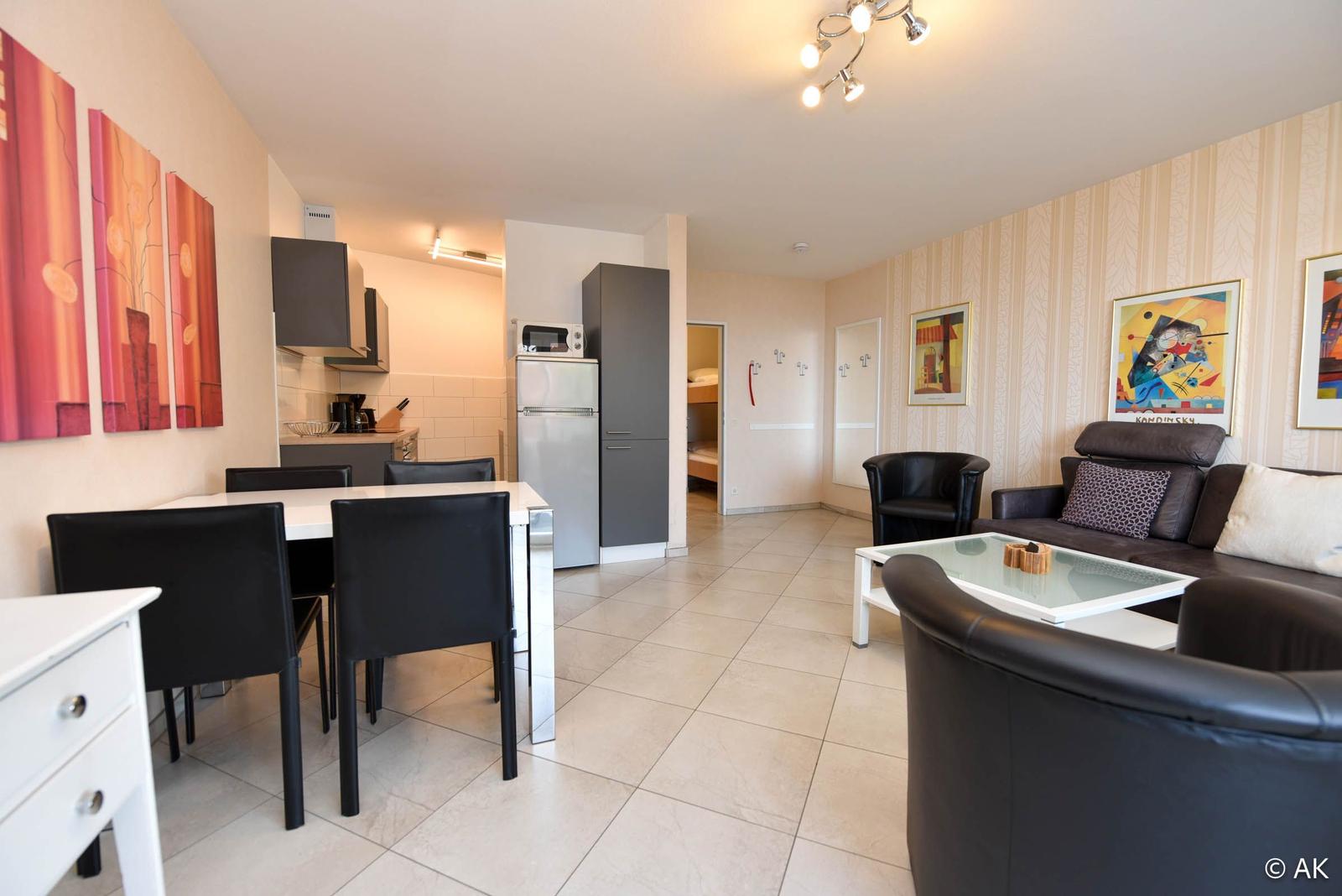 Wohnung mit Essbereich, Küche und Wohnzimmer mit Sofa und Sessel.