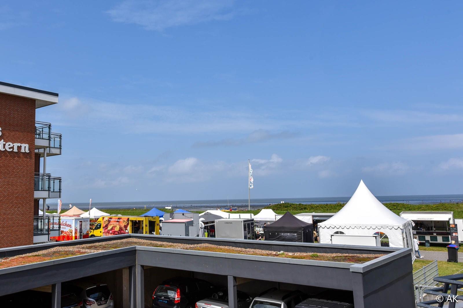 Rooftop-Parkplatz mit Blick auf Strand und Marktzelte.