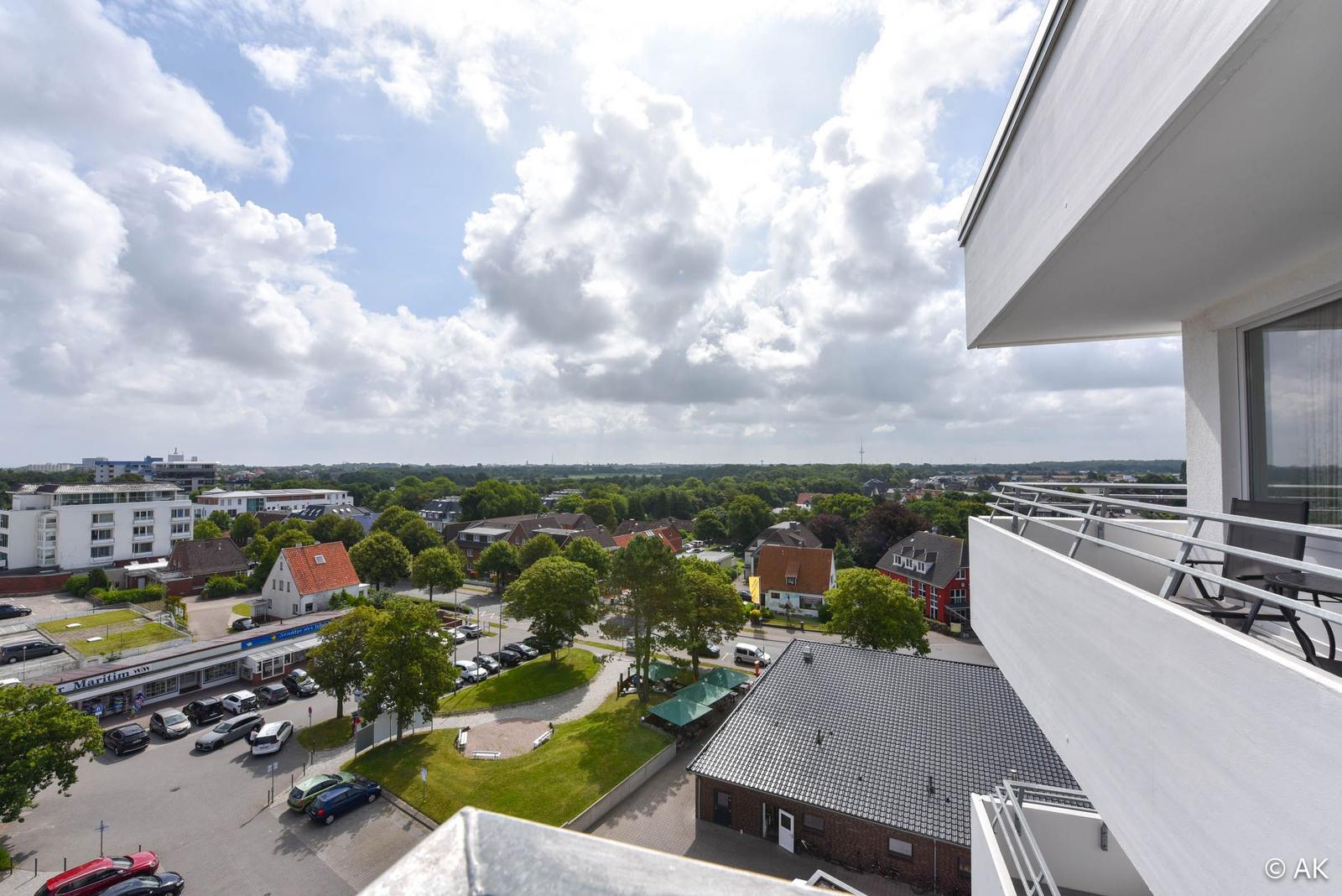 Blick von Balkon auf Stadt mit Grünflächen und Parkplatz