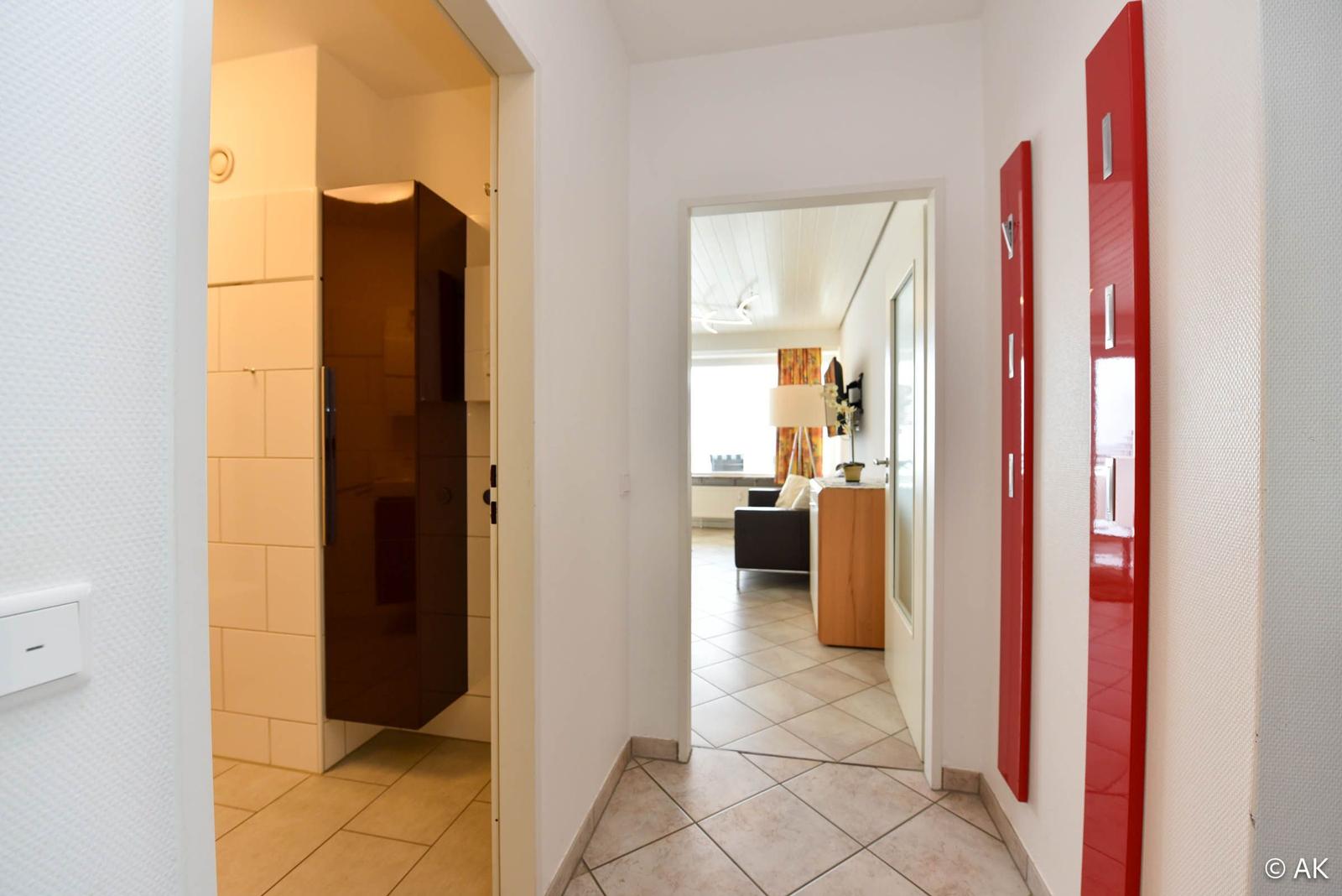 Flur mit Blick in Bad und Wohnzimmer. Rote Schrankwand an der Wand.