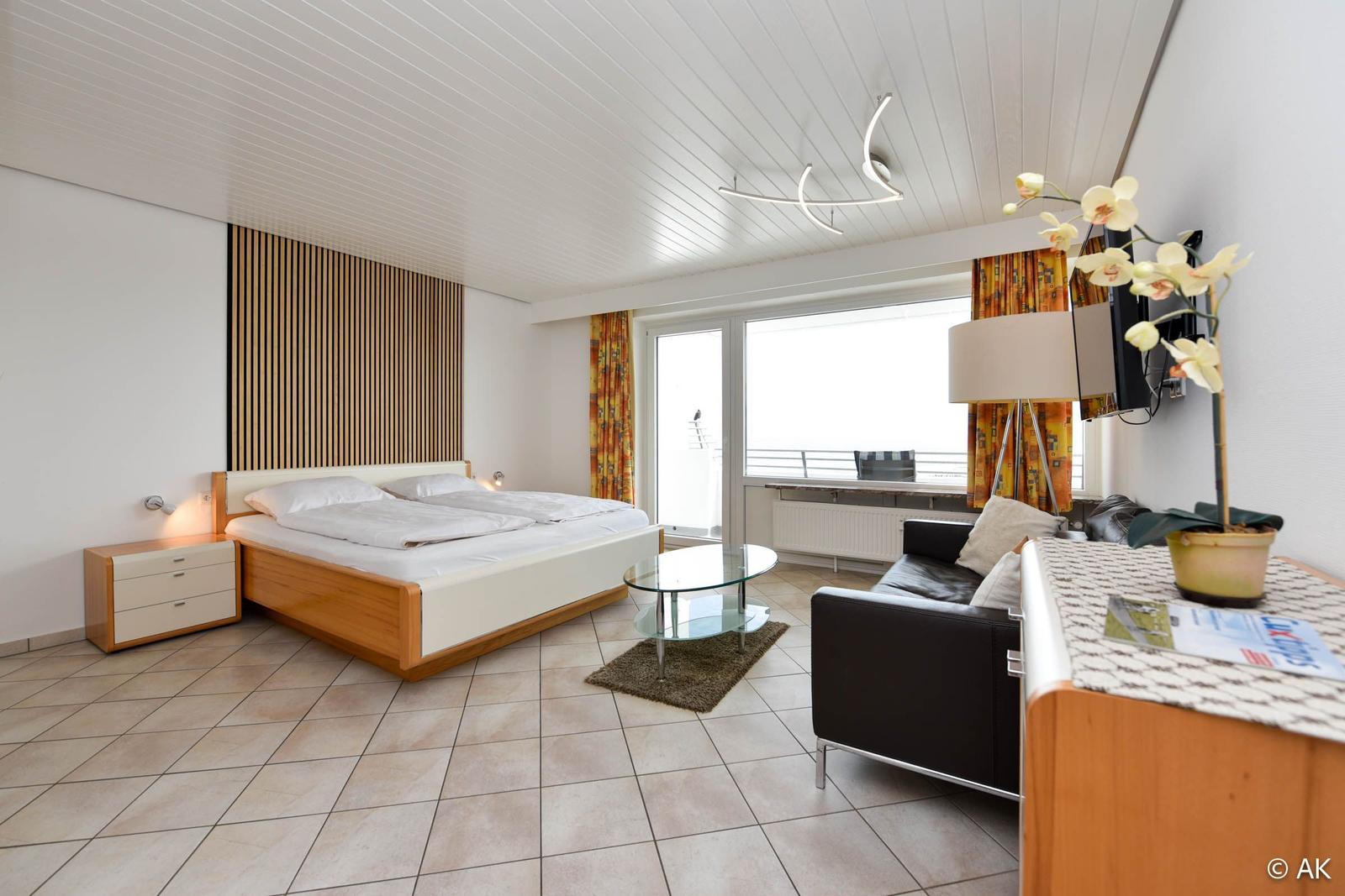 Schlafzimmer mit Doppelbett, Sofa und Balkonansicht.