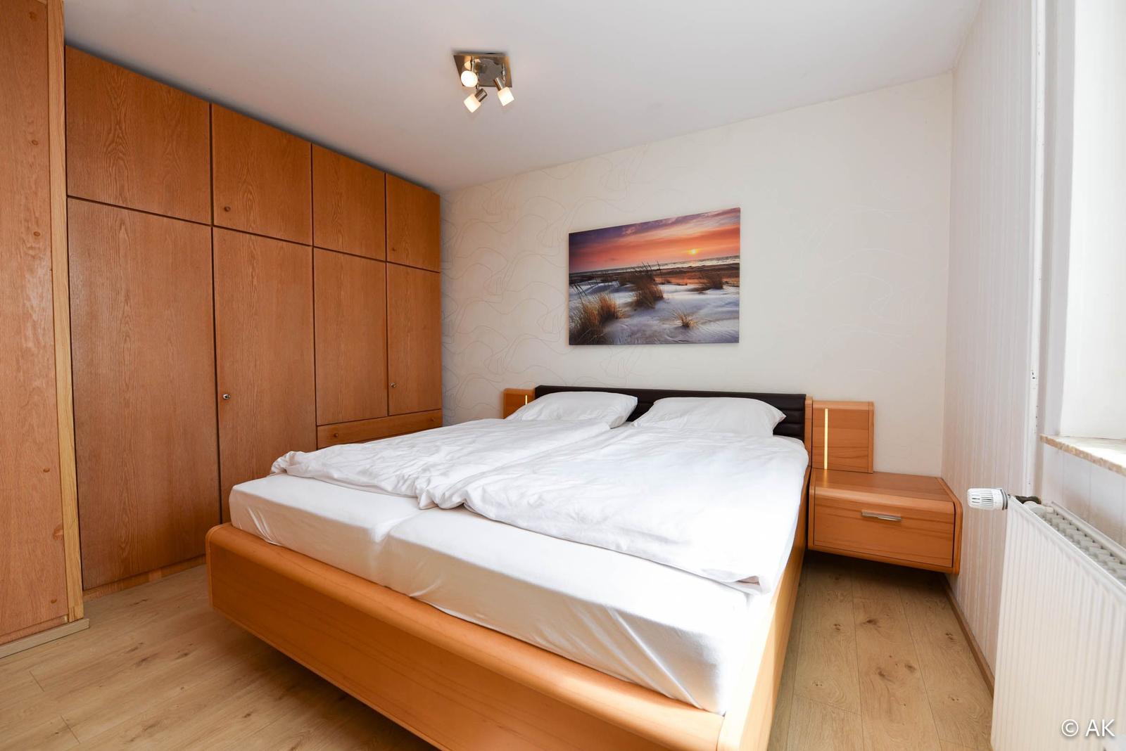 Schlafzimmer mit Doppelbett, Holzmöbel und Wandbild
