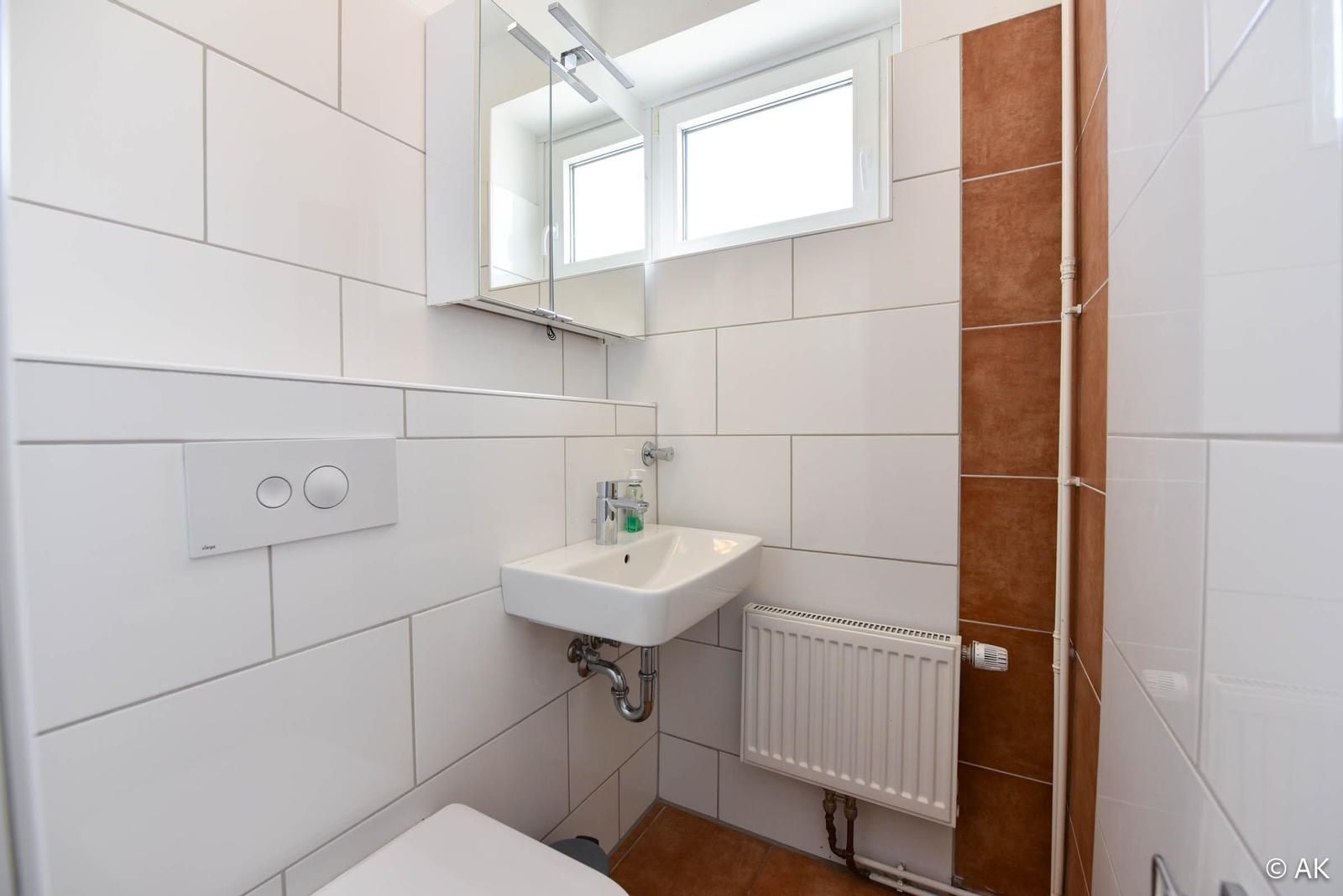 Badezimmer mit Waschbecken, Spiegel und Fenster