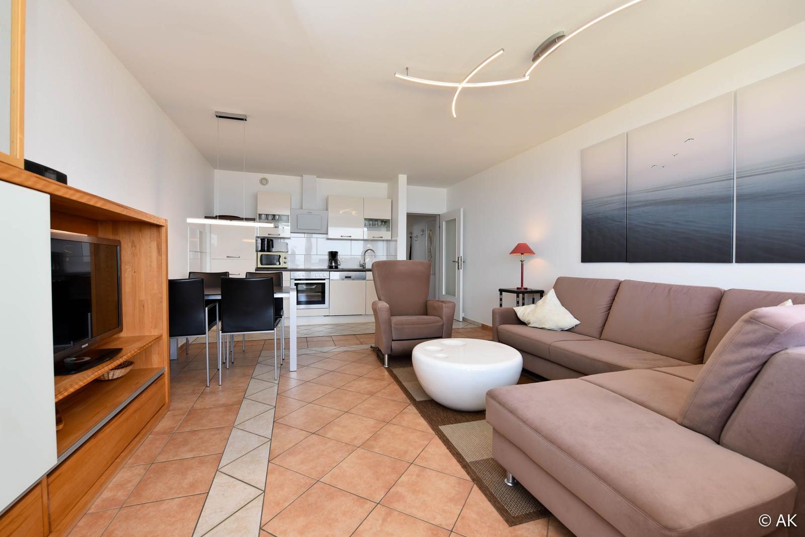 Wohnzimmer mit Sofa, Couchtisch und Küchenbereich im Hintergrund.