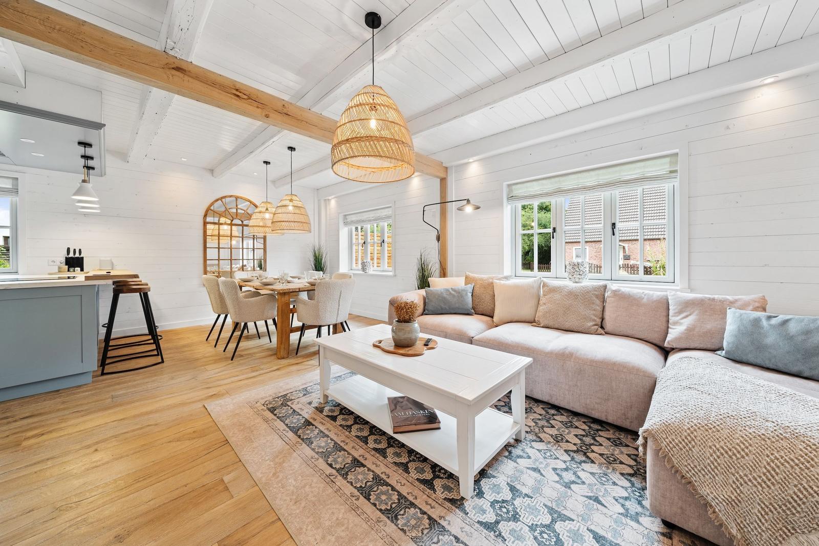 Wohn- und Essbereich mit Holzboden, Sofa, Tisch und Kücheninsel.