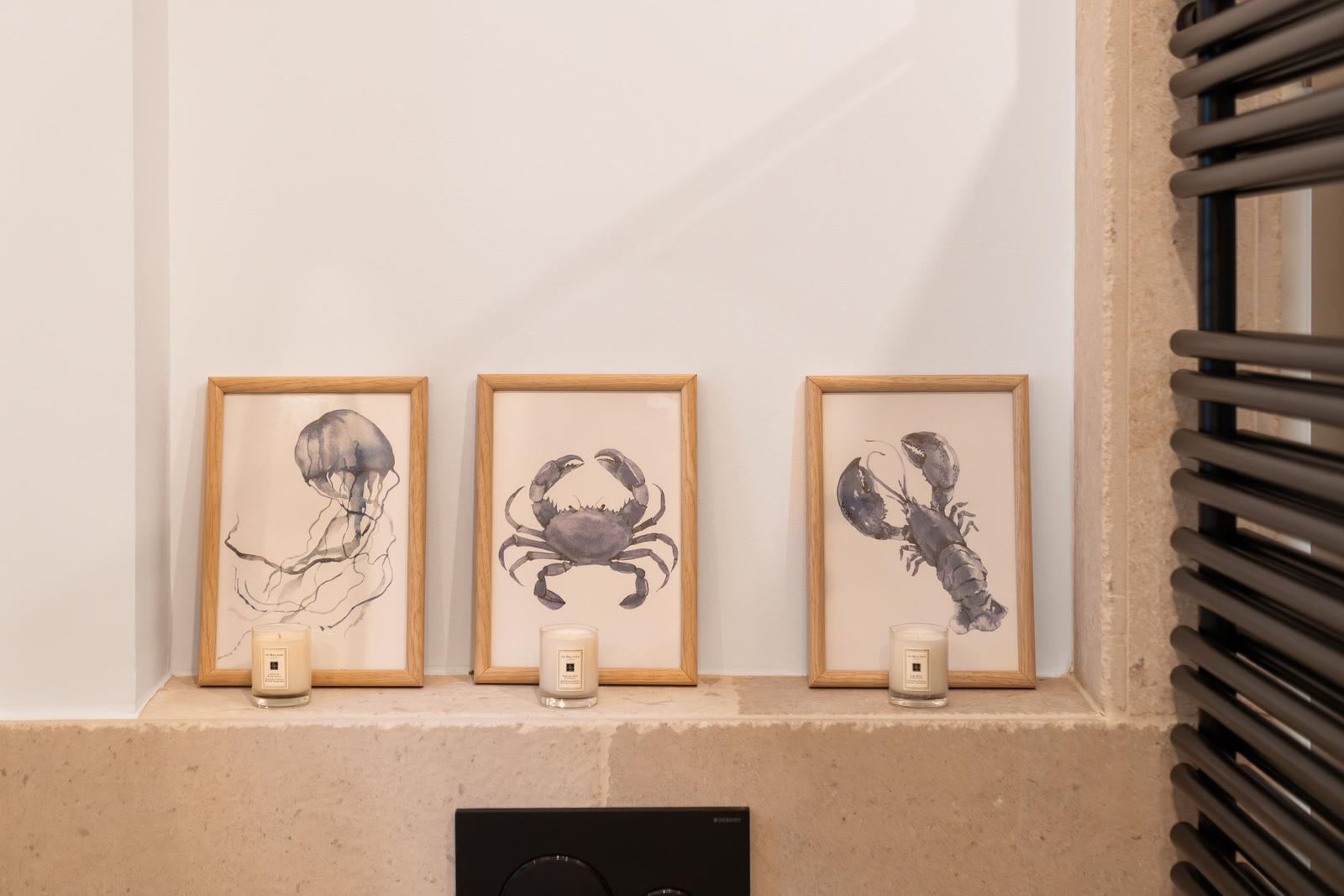 Drei gerahmte Meereslebewesen-Bilder mit Kerzen auf einer Steinbank.