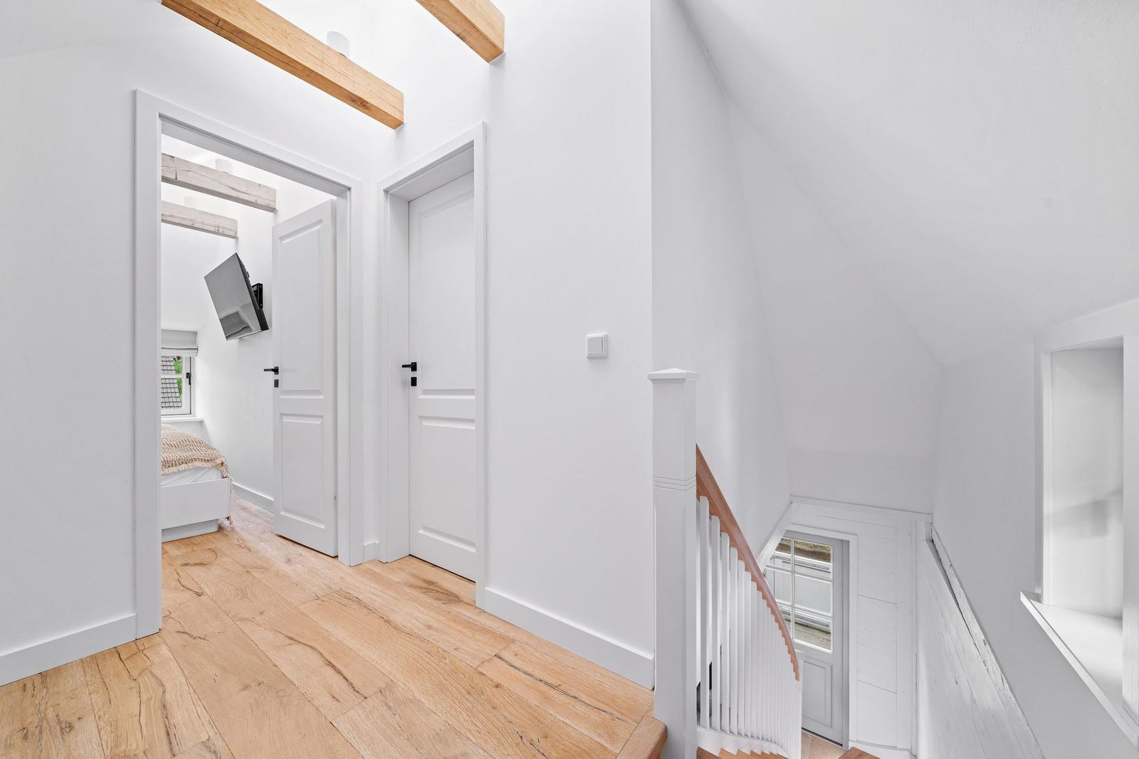 Helle Eingangshalle mit Holzboden und Treppe zur oberen Etage.