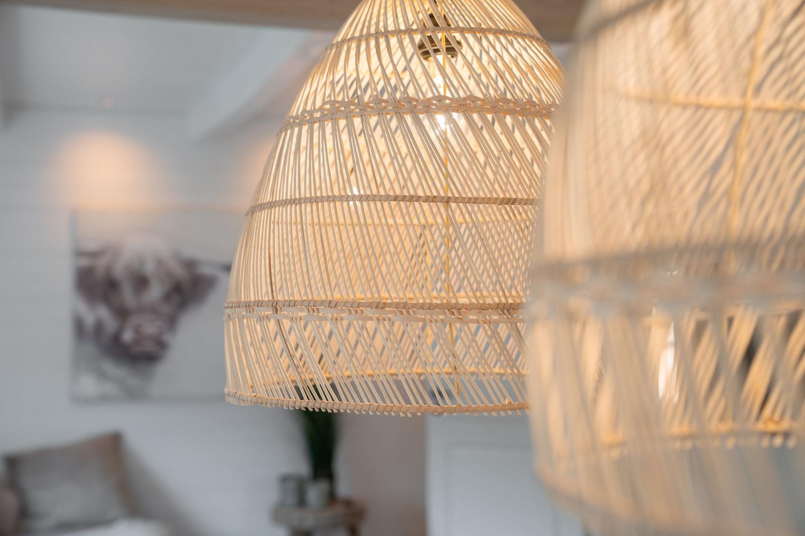 Rattan-Lampen hängen im Wohnbereich. Wandbild mit Tiermotiv im Hintergrund.