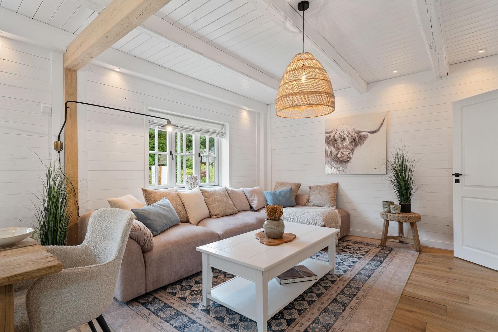 Wohnzimmer mit Sofa, Tisch und Wandbild. Holzdecke und Boden.