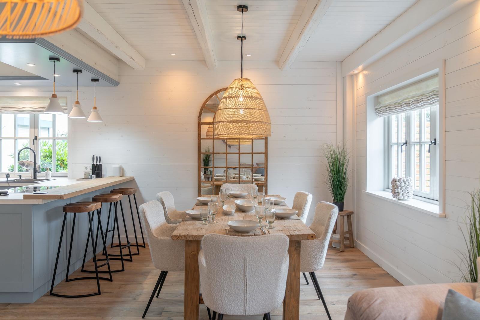 Essbereich mit Holztisch, Stühlen und Kücheninsel. Decke mit Balken und Fenster.