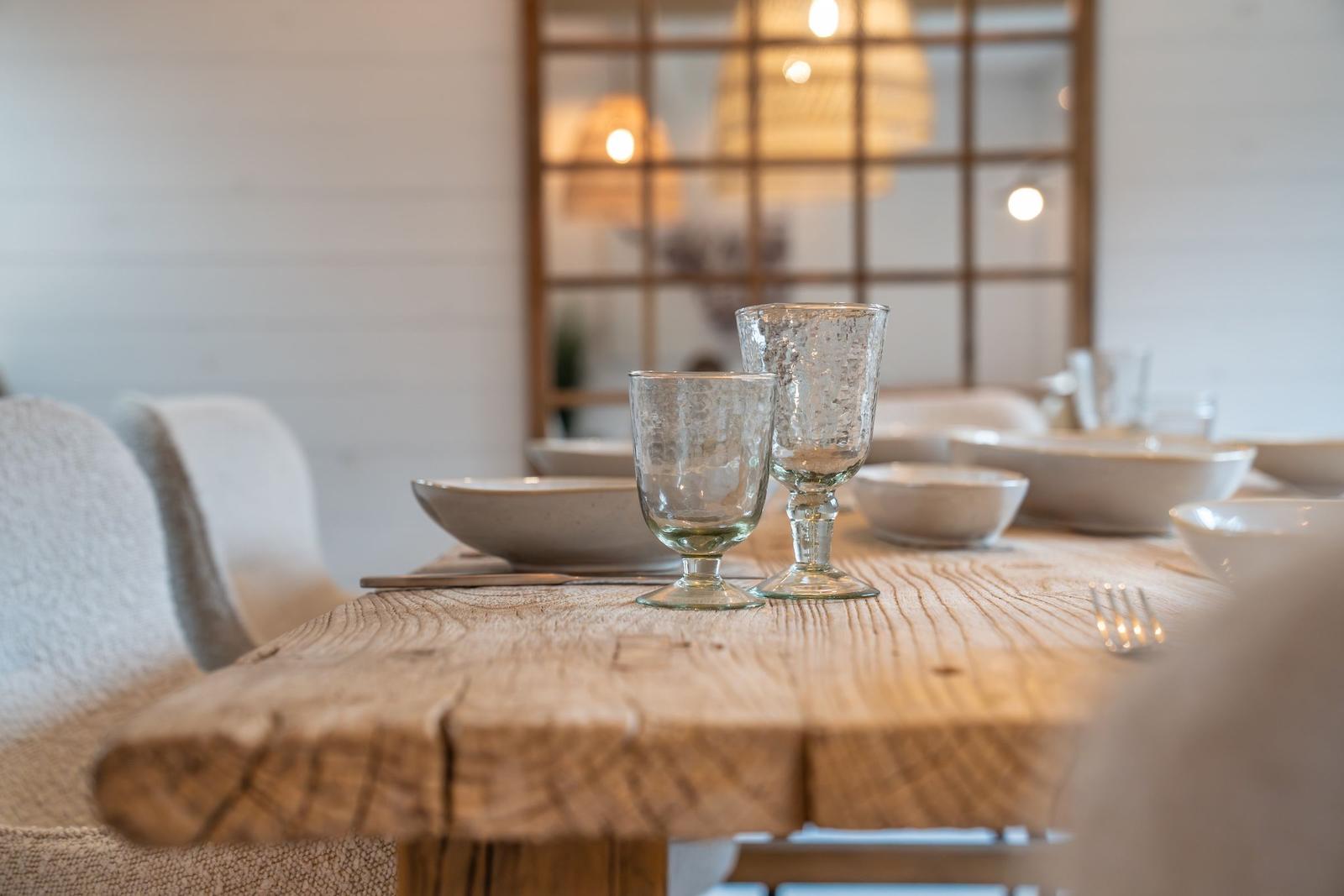 Holztisch mit Geschirr und Gläsern, Hintergrund mit Holzfenster und Lampen