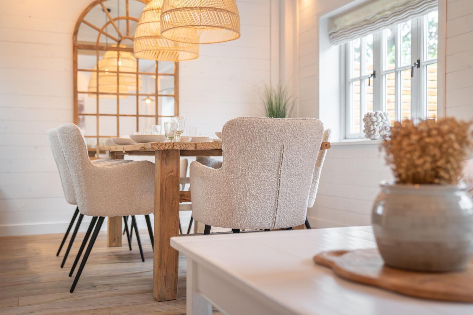 Essbereich mit Holztisch, Stühlen und Deckenleuchten. Fenster mit Jalousie und Pflanzen.